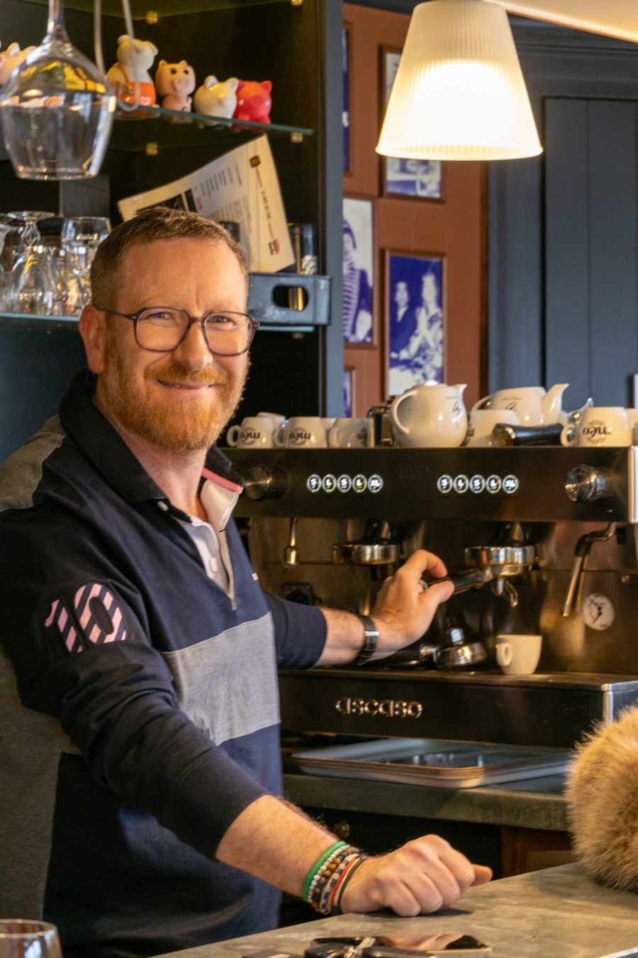 Alex, le patron du Triez, souriant devant la machine à café du bar à Mouvaux