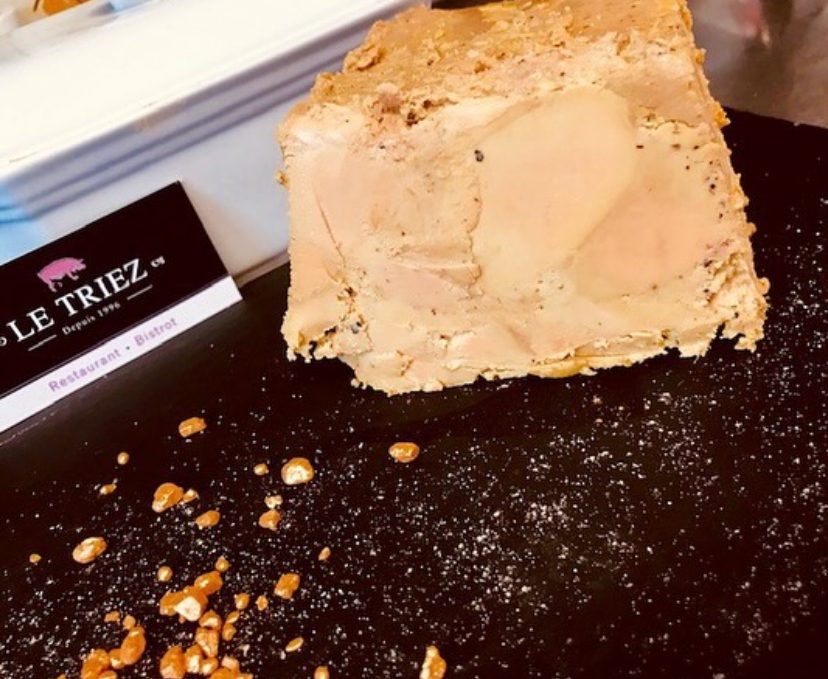 Une tranche de foie gras de canard maison du Triez sur une ardoise, avec la carte du restaurant