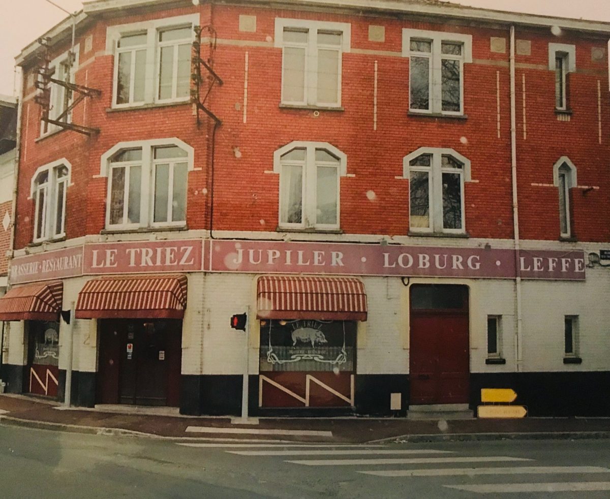 Ancienne façade du restaurant Le Triez à Mouvaux, avec ses stores rayés rouges, l'enseigne Brasserie Restaurant Le Triez et la vitrine au cochon