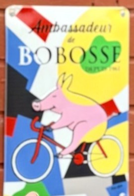 Plaque émaillée Ambassadeur Bobosse, avec un cochon rose à bicyclette, sur la façade du Triez