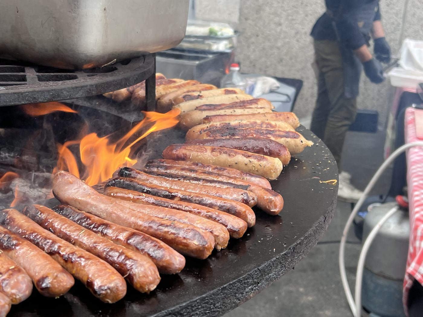 Saucisses grillées sur la plancha ronde, au feu de bois